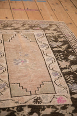 Angled detail of the stepped spandrel and charcoal brown floral border on a vintage Oushak rug.