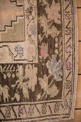 Worn texture of a vintage Oushak corner showing its stepped spandrel and floral border.