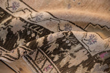 A fold in the distressed Oushak rug reveals the textured hand-knotted pile and even wear.