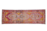 Distressed Oushak runner with interconnected floral medallions in purple, saffron, tangerine, 3x8.7 feet.