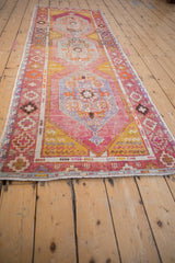 Distressed Oushak runner's pale purple elongated medallion with orange floral bouquet.