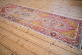 Distressed Oushak runner with geometric border and faded pink, saffron, blue motifs.