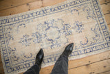 Top-down view of a distressed vintage Oushak rug showing its worn ivory and blue pile.