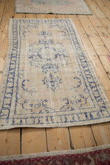High-angle view of a distressed ivory and blue vintage Turkish Oushak rug.
