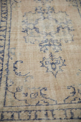 Worn knot heads and cobalt blue design on a vintage Oushak rug's ivory foundation.