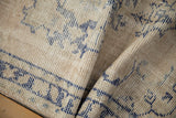 Close view of the worn hand-knotted pile and ivory wool foundation on a distressed Oushak rug.