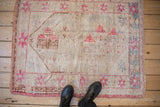 Distressed Oushak rug detail with faded pink pictorial villas and starburst border.