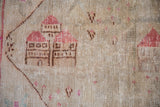 Detail of pictorial villa motif in raspberry and brown on worn ivory vintage Oushak rug.