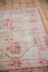Detail of vintage Oushak rug, with worn pile, visible foundation, and pale pink designs.