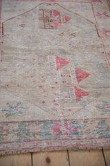 Faded raspberry and cream pictorial villa motifs on a distressed vintage Oushak rug.