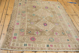 Distressed beige Oushak rug pile with faded fuchsia and turquoise floral designs.