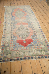 Distressed Oushak runner detail: dusty rose medallion, denim blue starburst border, visible wear.