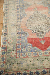 Distressed vintage Oushak rug runner corner, with worn starburst border and dusty rose field.