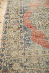 Vintage distressed Oushak runner with blue starburst border and textured dusty rose field.