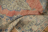 Distressed Oushak runner's textured pile, with heavy abrashes of dusty rose and denim blue.