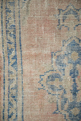 Distressed pile of vintage Oushak rug runner, featuring dusty rose, sky blue, and ivory tones.