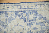 Close-up of vintage Oushak rug showing cobalt blue border motifs and worn ivory texture.