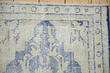 Distressed vintage Oushak rug with visible cream foundation and cobalt blue motifs.