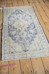 Distressed vintage Oushak rug showing faded cobalt blue floral patterns and worn foundation.