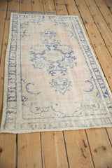 Vintage Oushak rug's abrashed dusty rose field and cobalt blue pattern, viewed from an angle.