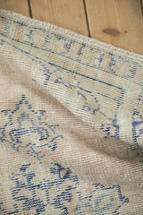 A folded corner of a vintage Oushak rug showing its soft, low-pile texture and secured end.