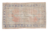 Distressed vintage Oushak rug with a blush starburst medallion and cobalt blue border.