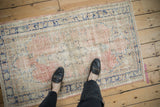 Overhead view of a distressed Oushak rug, showing its worn texture with blush, ivory, and blue tones.