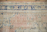 Distressed texture of a vintage Oushak rug showing foundation under blush and cobalt blue knots.