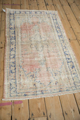 Distressed vintage Oushak rug with a faded blush and blue pattern, shown at an angle.