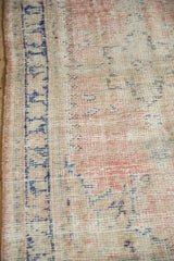 Restored side cord selvage and worn, hand-knotted texture of a distressed Oushak rug.