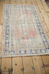 Angled view of a distressed Oushak rug highlighting its decorative wear in blush and cobalt blue.