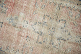 Close-up on the distressed Oushak rug weave, showing wear across the blush and ivory knot heads.