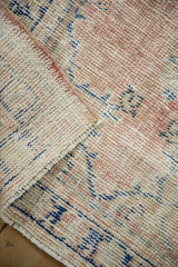 Corner of a distressed Oushak rug folded to show the hand-knotted foundation and worn wool pile.
