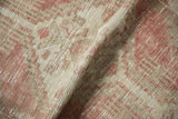 The distressed, low pile of a vintage Oushak rug showing visible knot heads and foundation.