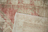 Corner of a distressed Oushak rug folded to reveal the hand-knotted foundation and worn pile.