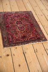 Angled view of a vintage American Sarouk rug mat showing its cherry red and navy floral design.