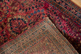 Folded corner of a fine Sarouk rug showing the dense red pile and its hand-knotted back.