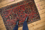 Vintage Lilihan rug with a raspberry red field and navy vinery, viewed from above for scale.