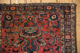Corner detail of a vintage Lilihan rug showing the tattered edge and navy floral border.