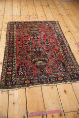 Angled view of a vintage Lilihan rug with a red field and central navy vase design.
