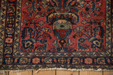 Worn corner of a vintage Lilihan rug showing the navy floral border and tattered fringe.