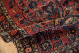 Folded vintage Lilihan rug displaying its low pile, knot heads, and delicate vinery in red and navy.