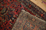 A folded corner displays the hand-knotted pile and woven foundation of a vintage Persian rug.