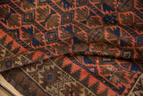 Folded vintage Belouch runner, showing serrated geometric motifs in chocolate, terracotta, and navy.