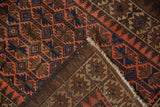 Hand-knotted construction of a vintage Belouch runner, showing its worn fringe and geometric pattern.