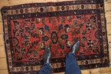 A person standing on a fine vintage Mehreban rug with raspberry and blue floral patterns.