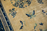Worn cream field and cobalt Greek key border of a vintage Peking rug.