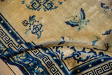 Vintage Peking rug revealing dark blue geometric border and cream field texture.