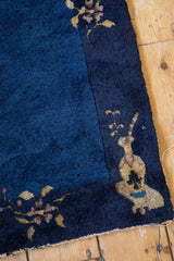 Navy blue field with beige vase border motif and visible selvage on a vintage Peking rug.