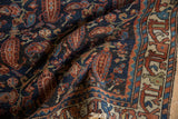 Folded vintage Mehreban rug detail, displaying madder red paisley botehs, vinery, and ivory border.
